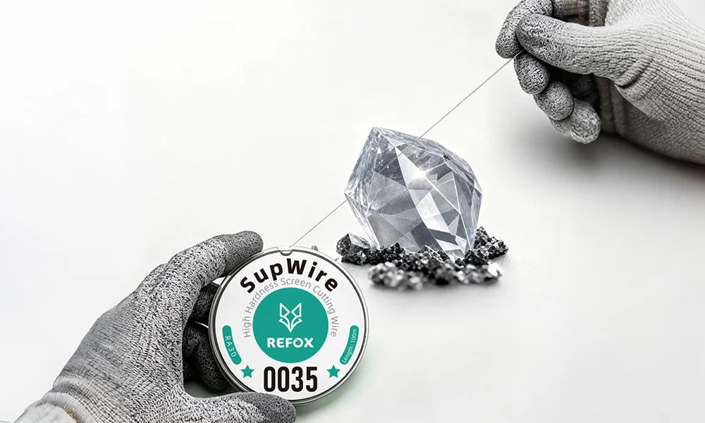 A close-up of a diamond wire saw spool labeled 'SupWire REFOX 0035' held by a gloved hand, with another gloved hand guiding a wire loop near a faceted clear gemstone on a white background.