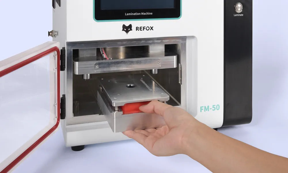 Hand inserting a red object into a REFOX lamination machine on a white background