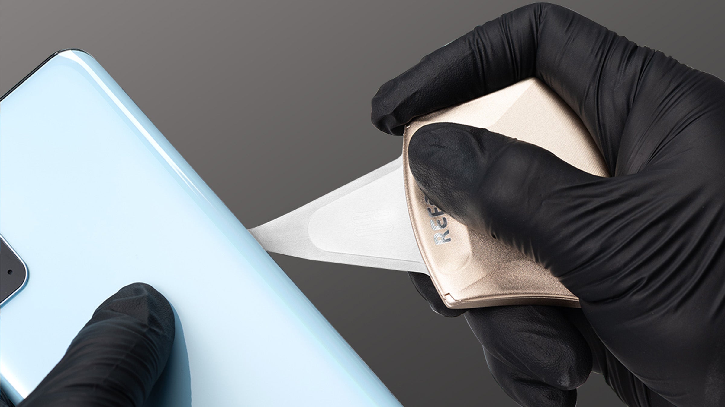 Person wearing black gloves holding a smartphone and a RS70 Pry blade kit on a gray background