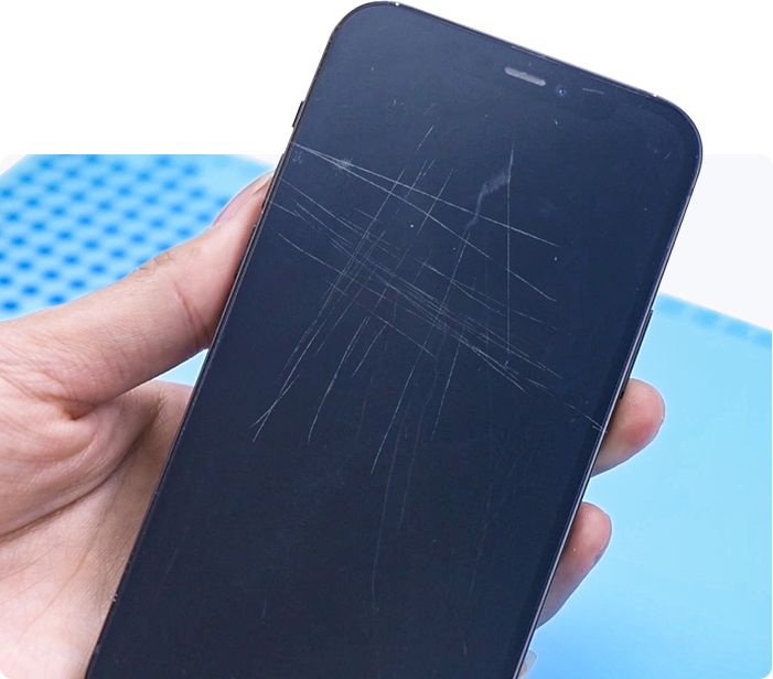 Hand holding a smartphone with a cracked screen against a blue background