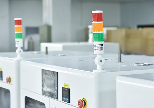 Two red, yellow, and green signal lights on a polishing machine