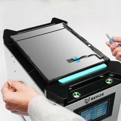 Person using a REFOX device to repair or process an electronic component on a white background