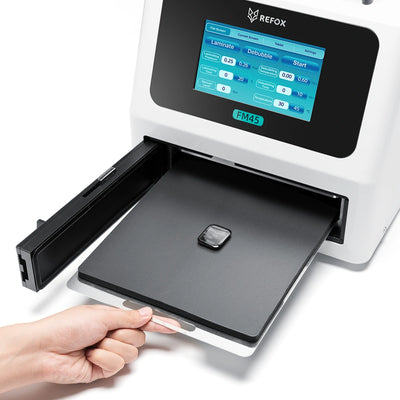 Hand holding a small device above a REFOX machine with a digital display.