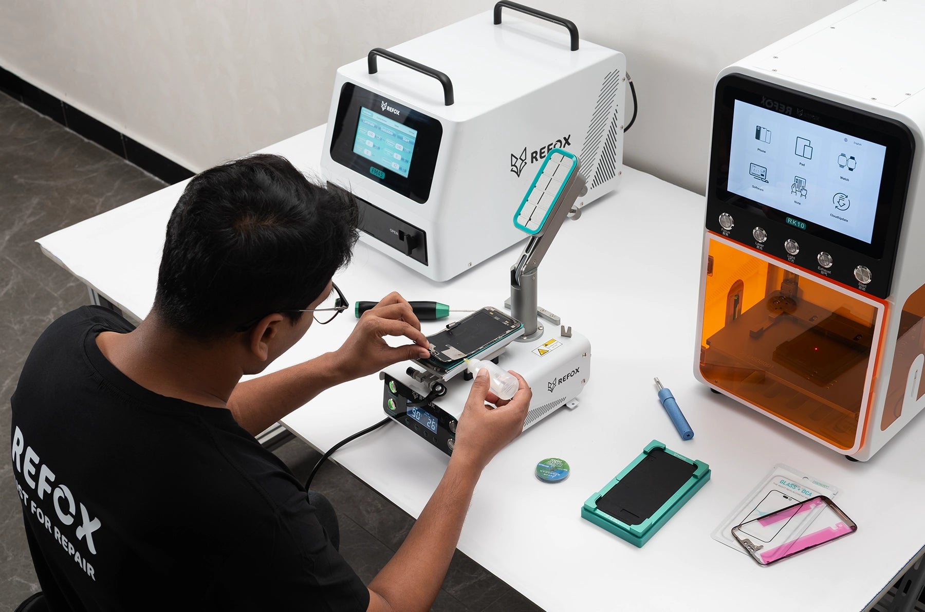 Person working on a smartphone repair with REFOX equipment in a workshop setting