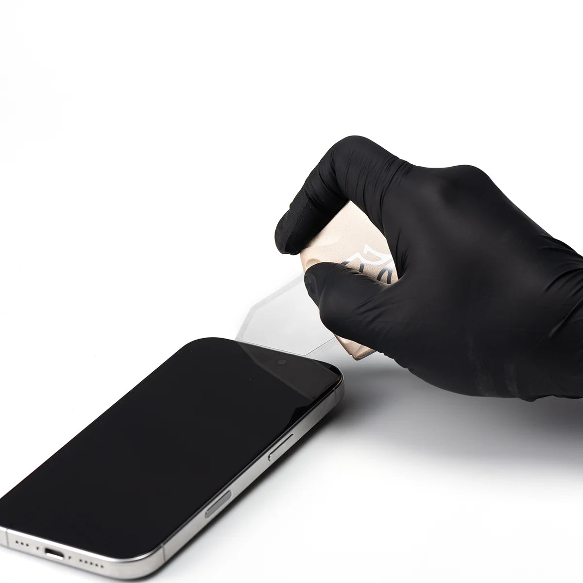 Hand wearing a black glove cleaning a smartphone screen on a white background