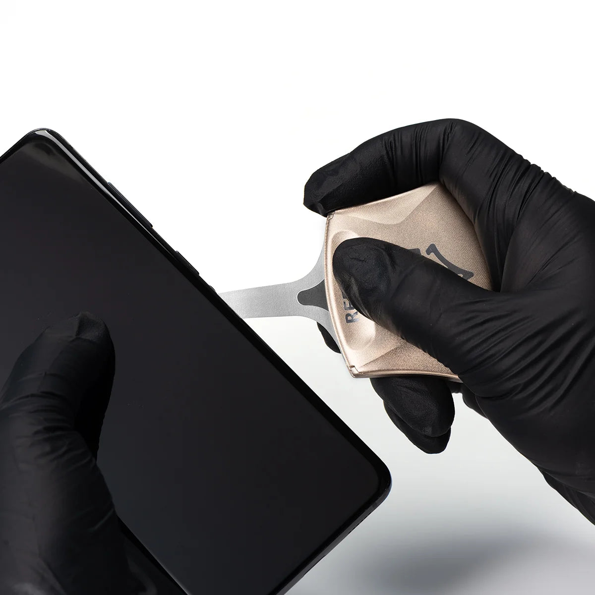 Person wearing black gloves using rs70 pry tool opening a smartphone screen