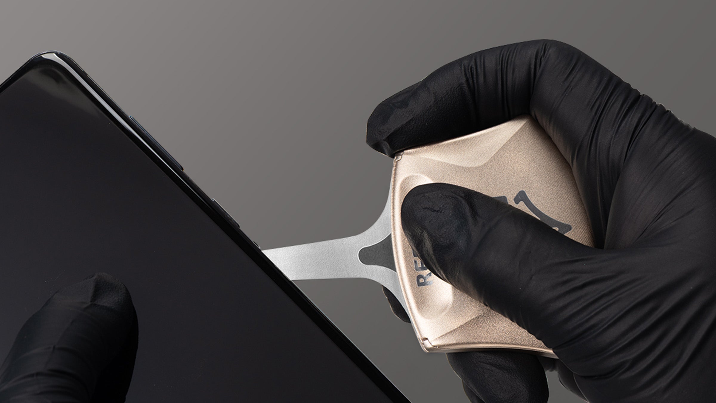 Person wearing black gloves using a rs70 pry tool kit against a gray background